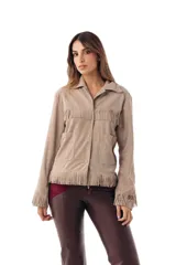 Campera de gamuza color crudo con flecos en el pecho, en el ruedo y en las mangas, cuello camisero, bolsillos frontales appliqués y cierre con broches a presión oculta.
