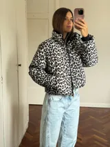 Campera puffer con estampado de leopardo en tonos blanco y negro, cuello alto, cierre frontal y bolsillos laterales.