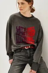 Buzo de cuello redondo y manga larga, confeccionado en algodón y viscosa con efecto lavado. Presenta un estampado frontal con tipografía en tonos degradados de violeta a rojo.