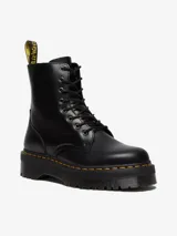Borcego negro de cuero liso pulido, con plataforma gruesa y suela ranurada. Presenta costuras amarillas distintivas, cordones negros y una cremallera interior para facilitar su calce. Incluye el clásico lazo negro y amarillo en el talón.
