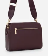 Cartera bandolera de tamaño mediano en cuero sintético color bordó, con formato rectangular y múltiples compartimentos con cierre de cremallera. Incluye correa de hombro ajustable en grosgrain y herrajes metálicos dorados.