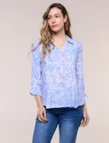 Blusa celeste con estampado efecto pincelada blanca, de corte semi holgado, escote en V con cuello solapa y media abotonadura frontal con botones nacarados. Presenta finas alforzas verticales en la pechera y mangas 3/4 con puños elastizados.