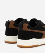 Championes masculinos de estilo street, confeccionados en material sintético color negro con recortes laterales en color marrón. Poseen cierre de cordones, puntera redonda, entresuela blanca y suela de goma color caramelo.