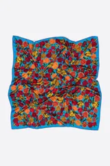 Pañuelo cuadrado estampado con rosas en tonos rojos, naranjas y amarillos sobre un fondo azul vibrante. Confeccionado en poliéster reciclado.