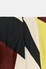 Falda midi de corte cruzado con diseño tipo pareo, presenta un nudo decorativo en la parte delantera y cierre de cremallera oculta en la espalda. El tejido cuenta con un estampado geométrico abstracto en tonos bordó, negro, amarillo y crema.