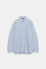 Camisa oversize de manga larga con cuello solapa, cierre frontal de botones y bolsillo de parche en el pecho, con diseño de rayas verticales celestes y blancas.
