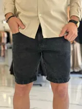 Bermuda de jean negro, de corte slouchy, con bolsillos laterales y traseros, y cierre frontal de botón y cremallera.