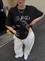 Remera marrón oversize con efecto acid wash, corte amplio y mangas cortas. Presenta un estampado frontal en tonos celestes y grises con la inscripción 'Sumo', una ilustración de un luchador de sumo y detalles tipográficos alusivos a un álbum musical.
