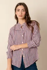 Camisa de lino a rayas verticales azules y blancas, con cuello mao, manga larga con puño elástico y cierre frontal con botones.