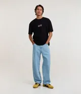 Remera negra de corte relajado, confeccionada en algodón, con cuello redondo y manga corta. Presenta un estampado gráfico en la espalda en color rosa que ilustra diversos tipos de hongos junto con la frase 'Microworld full of life'.