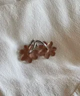 Aros de argolla metálica con dije colgante en forma de flor de acrílico color rosado.