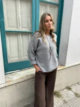 Sweater de punto color gris, de corte holgado, cuello redondo y mangas largas con puños doblados.