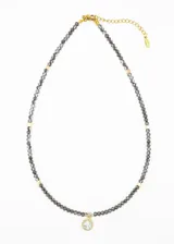 Gargantilla de mostacillas grises con detalles de acero quirúrgico dorado y dije circular con strass.