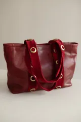 Cartera grande de cuero color marrón con asas de cuero con estampado animal print y ojales dorados.