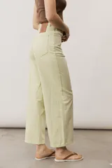 Pantalón de jean verde lima, de corte recto y tiro alto, con bolsillos traseros y etiqueta de cuero con logo en la parte posterior.