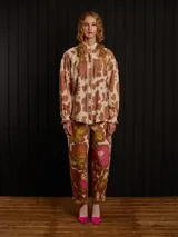 Pantalón de gabardina color marrón con estampado floral, corte carrot fit, tiro medio, estilo carpintero y detalles de botón de metal personalizado y parche trasero personalizado.