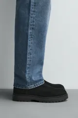 Bota estilo Chelsea de hombre, fabricada en piel con acabado de serraje. Presenta elásticos laterales, horma redonda y suela con ligero tacón.