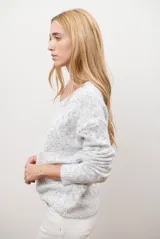 Buzo de punto color gris claro con motas oscuras, escote en V y mangas largas.