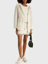 Parka color crema con capucha, cierre frontal con cremallera y bolsillos con solapa.