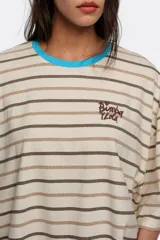 Remera boxy de algodón orgánico con diseño a rayas horizontales en negro y crudo, escote redondo con ribete amarillo, mangas cortas amplias y pequeño bordado en el pecho.