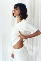 Pijama de algodón color blanco natural, compuesto por una remera de manga corta con bordado a contratono en el pecho y un pantalón largo de corte relajado con cordón ajustable en la cintura.
