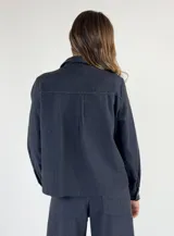 Chaqueta tipo camisa de denim color borgoña, con cuello clásico, manga larga, cierre frontal con botones y bolsillo de parche en el pecho.