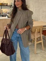 Blazer de corte relajado con diseño cuadrillé en tonos beige y marrón. Presenta hombros levemente estructurados, cierre cruzado con un botón y solapas clásicas.