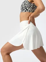 Falda short deportiva blanca, de talle alto con cintura cruzada en forma de V. Cuenta con aberturas laterales y short interior con bolsillo.