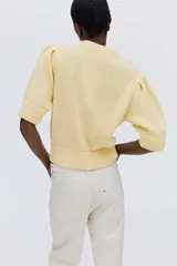Top de punto acanalado color amarillo, con cuello redondo, mangas cortas abullonadas y terminaciones acanaladas en puños y ruedo.
