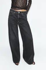 Jeans de tiro medio y corte wide leg en color marrón oscuro, con diseño de cinco bolsillos y cierre frontal con cremallera y botón metálico.