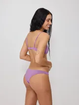 Top de bikini con tirantes finos y escote redondo, confeccionado en poliamida con elastano, con estampado tropical en tonos verdes, celestes y salmón sobre fondo negro.