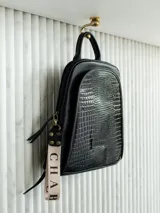 Mochila negra de cuero natural con detalles en charol y correa con la palabra "CHARB".