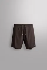Pantalones cortos de entrenamiento 2 en 1 de color marrón, confeccionados por Zara Athleticz en tejido técnico ligero y elástico con malla interior. Cuenta con cintura elástica ajustable con cordón y bolsillos laterales.