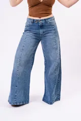 Jean de corte wide leg con costura central vertical en ambas piernas. Presenta un tono denim clásico, tiro medio y cierre frontal con botones.