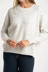 Sweater de punto con diseño jaspeado, cuello redondo y corte oversize. Presenta costuras visibles en los hombros y puños acanalados.