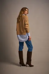 Sweater tejido color marrón claro, de escote redondo y calce holgado. Tiene hombros caídos, mangas largas y puños tejidos.