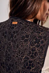 Chaleco sin mangas de corte al cuerpo, color negro con bordados florales en hilo contrastante. Presenta un diseño abierto con terminaciones reforzadas.