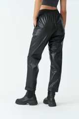 Pantalón negro de cuero sintético, tiro medio, con cintura ajustable, bolsillos laterales y corte holgado.