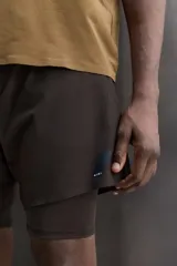 Pantalones cortos de entrenamiento 2 en 1 de color marrón, confeccionados por Zara Athleticz en tejido técnico ligero y elástico con malla interior. Cuenta con cintura elástica ajustable con cordón y bolsillos laterales.