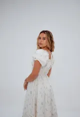 Vestido corto color crema con estampado floral, escote cuadrado con lazo ajustable, mangas cortas abullonadas y corte princesa.