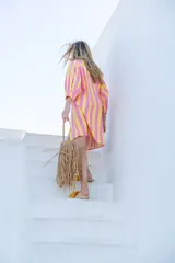 Vestido camisero a rayas verticales fucsias y amarillas, con cuello redondo, cierre frontal de botones y mangas largas abullonadas con puños elásticos.
