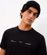 Remera de algodón de corte comfort, color negro, con cuello redondo y manga corta. Presenta un diseño minimalista con estampado de frases en tipografía blanca en la parte frontal.