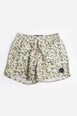 Short de baño celeste con estampado de hojas pequeñas en tonos verdes y blancos. Cuenta con cintura elástica con cordón ajustable, bolsillos laterales y un parche circular con logo en la parte inferior.