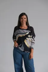 Sweater de punto con diseño abstracto en tonos negro, gris y blanco, con detalles en hilo dorado. Presenta cuello redondo, mangas tres cuartos con puños acanalados y un corte holgado.