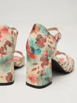 Sandalias de charol color blanco con múltiples tiras finas cruzadas en el empeine. Tienen pulsera con hebilla dorada y tacón cuadrado.