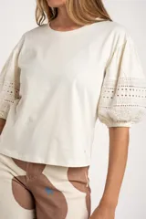 Remera negra de algodón con mangas tres cuartos abullonadas y detalle de bordado calado tipo ojal en la zona del antebrazo.