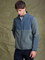 Campera de polar con cierre frontal completo, cuello alto y bolsillo en el pecho con cierre. Presenta un diseño combinado con paneles de tela técnica en la parte superior y polar en el resto de la prenda, con logo de la marca Benson & Thomas estampado en el hombro.