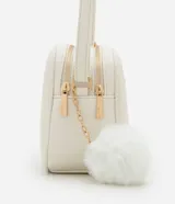 Cartera bandolera Satinato pequeña de color blanco, de diseño estructurado con textura floater, cierre de cremallera y detalles metálicos dorados. Incluye una correa larga ajustable y un pompón decorativo colgante.