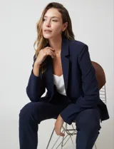 Blazer sastrero de corte entallado, color azul marino, con cuello de solapa, hombreras estructuradas y bolsillos laterales con solapa. Presenta cierre frontal con botón a tono y forro interno.