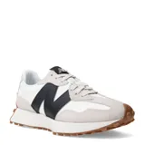 Championes urbanos New Balance modelo 327, con diseño retro inspirado en los años 70. Presentan una combinación de paneles de gamuza gris claro y base de nylon blanco, con el logo 'N' sobredimensionado en cuero sintético negro en el lateral. Incluyen una entresuela de espuma blanca y una suela de goma dentada que se extiende hacia el talón.